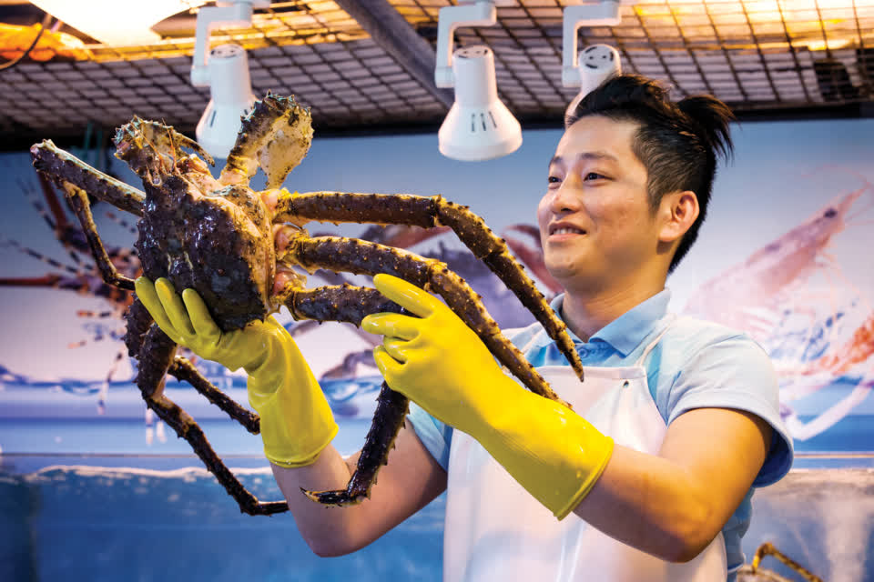 Stallholders in Link REIT fresh markets teach customers how to make seafood dishes with their produce.